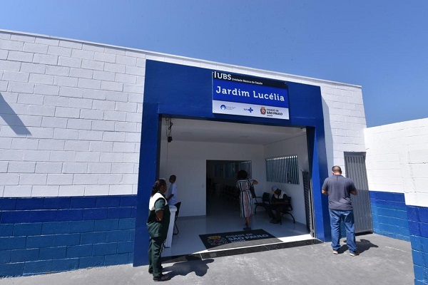 #PraCegoVer: Fachada da UBS Jardim Lucélia, com algumas pessoas na entrada do prédio.